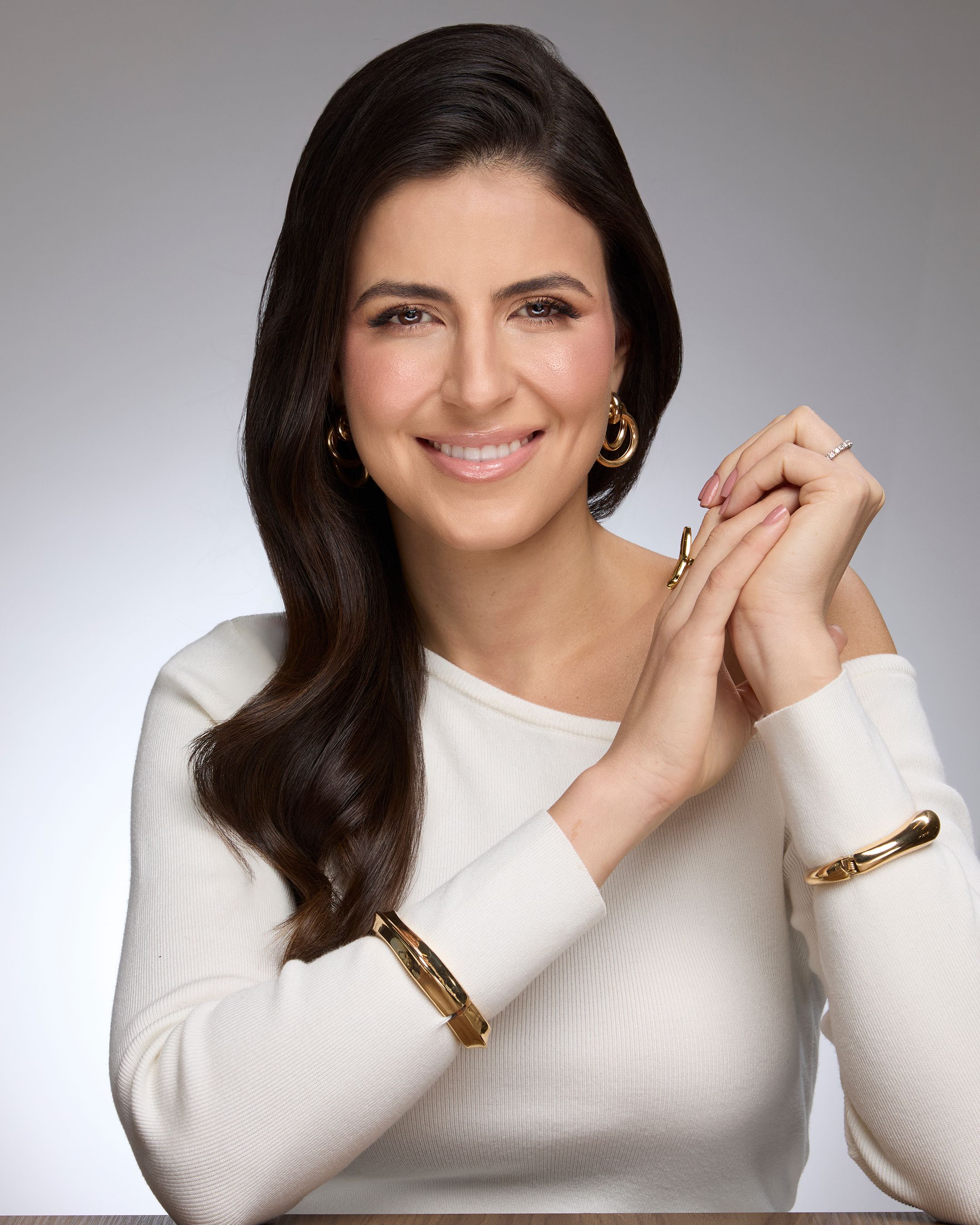 Dra. Gabriela Palermo, cirurgiã plástica, sorrindo, de blusa branca